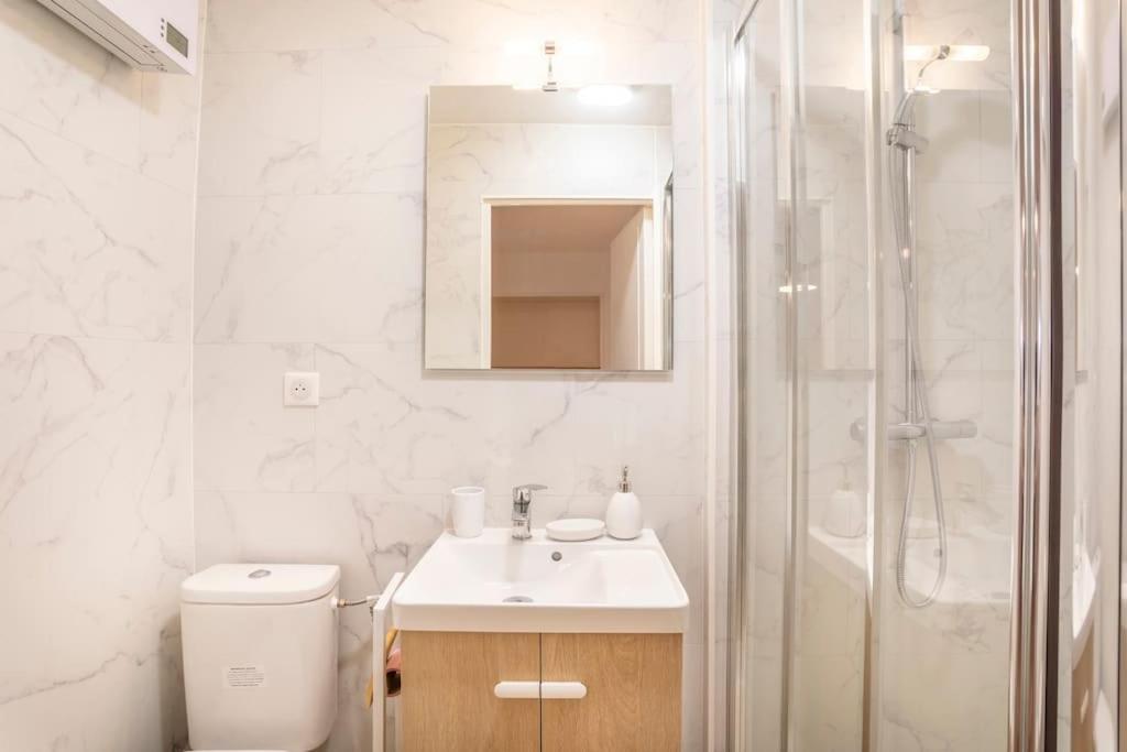 a white bathroom with a sink and a shower at Le nid de la Corderie in Marseille