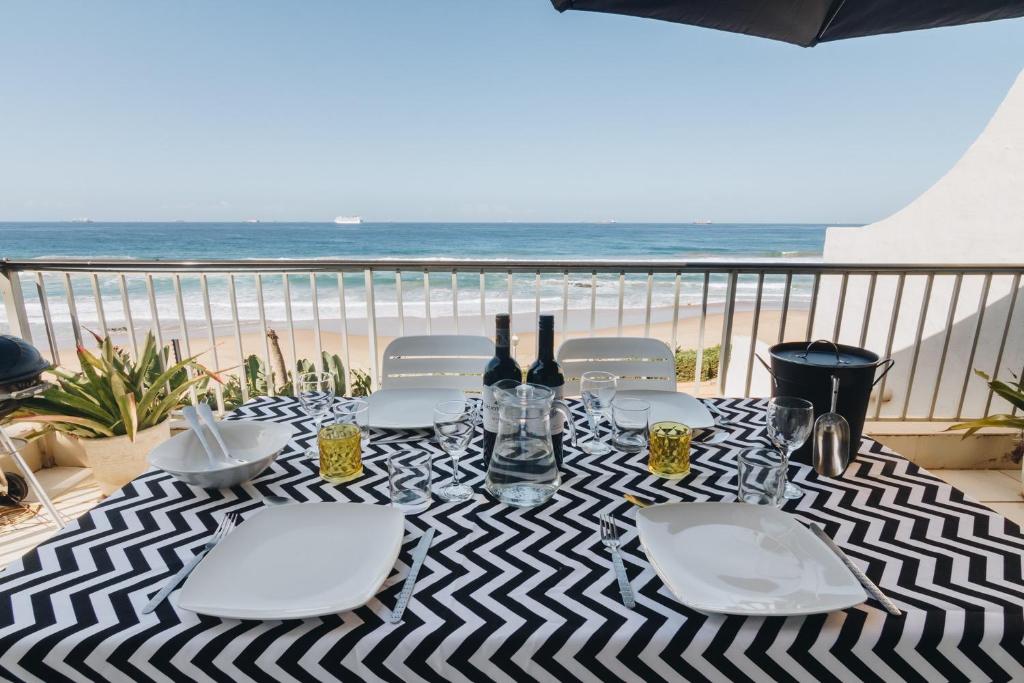 a table with wine bottles and chairs on the beach at 13 Bronze Bay in Durban