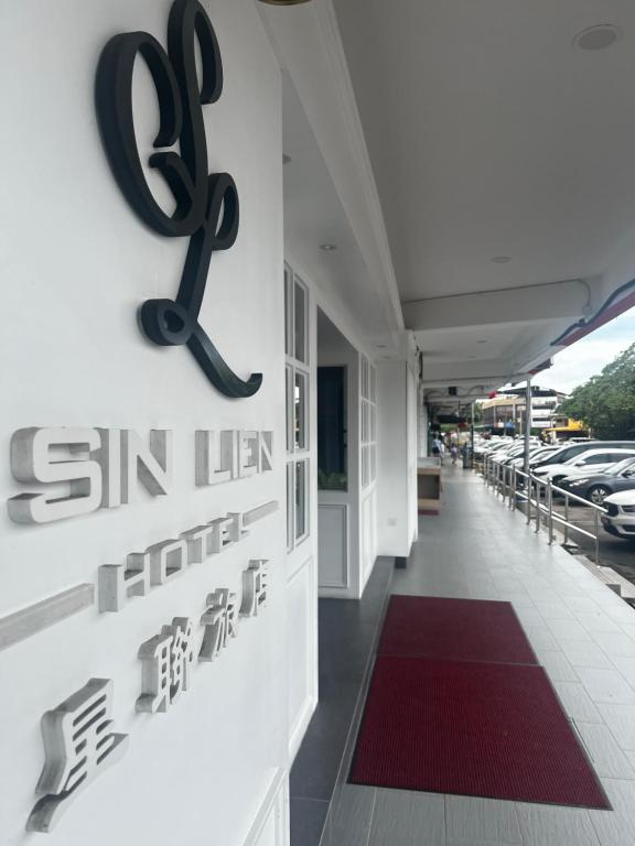 een bord aan de zijkant van een gebouw met geparkeerde auto's bij SiN LiEN HOTEL in Kluang