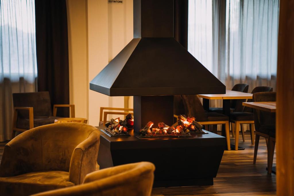 カスティオーネ・デッラ・プレゾラーナにあるEurohotel Mountain Wellnessの椅子付きの部屋の中央に暖炉