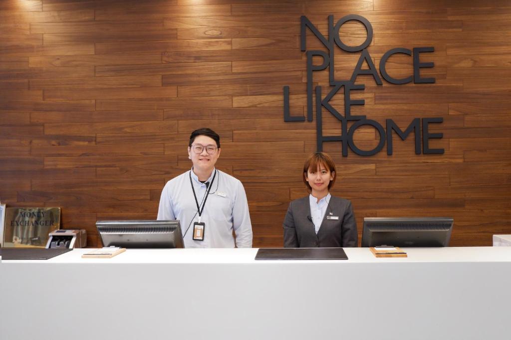 two people standing at a counter with a no place like home sign at Home Hotel in Taipei