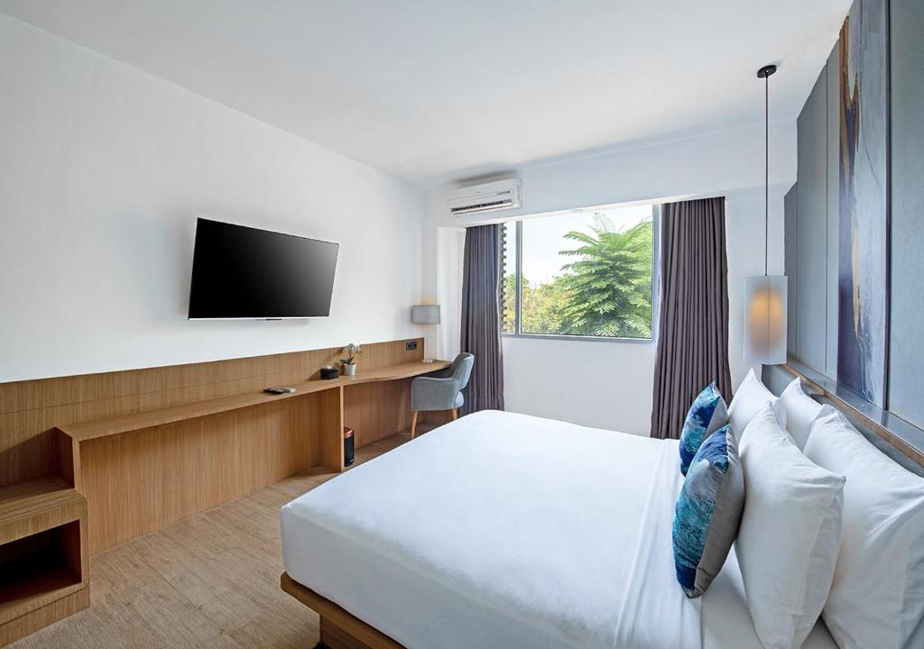 a hotel room with a bed and a flat screen tv at Oakwood Hotel & Apartments Taman Mini Jakarta in Jakarta