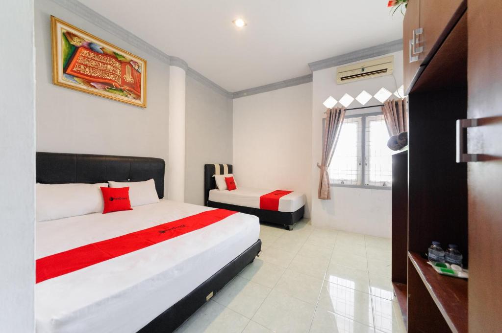 a bedroom with two beds and a window at RedDoorz Syariah near Suzuya Mall Banda Aceh in Banda Aceh