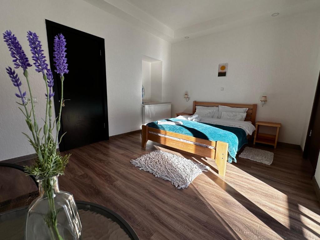 1 dormitorio con 1 cama y un jarrón con flores púrpuras en "White House Nakani" - Guesthouse near the centre en Mestia
