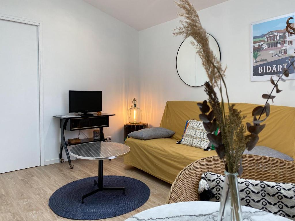 een woonkamer met een bank en een tafel bij Ilbarritz, T2 proche plage/parking/terrasse in Bidart