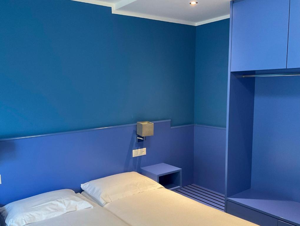 a blue bedroom with a bed and a blue wall at Hotel Liberty Self Check-In in Bellinzona