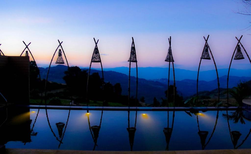 un groupe de moulins à vent reflétant dans l’eau au coucher du soleil dans l'établissement The Twelve Manor•Terraces Lodge, à Yuanyang