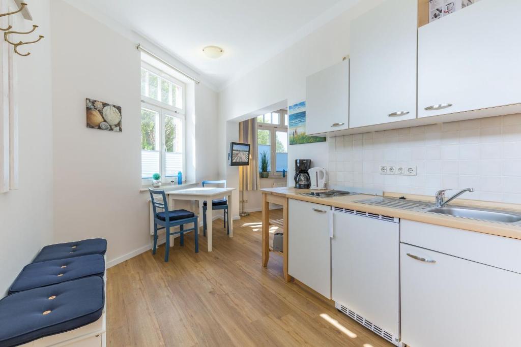 a kitchen with white cabinets and a table at Haus Tarnewitz, Ferienwohnung 04 in Tarnewitz