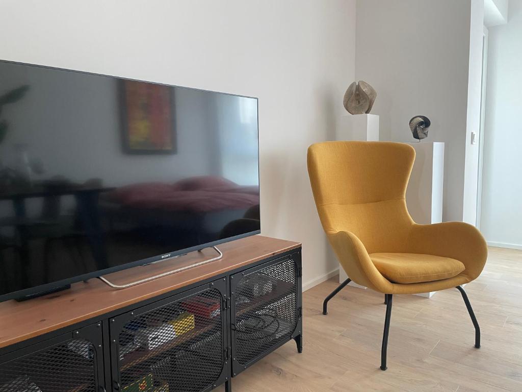 a yellow chair sitting in front of a television at Alma - Art Luxus Modern Ambiente in Karlsruhe