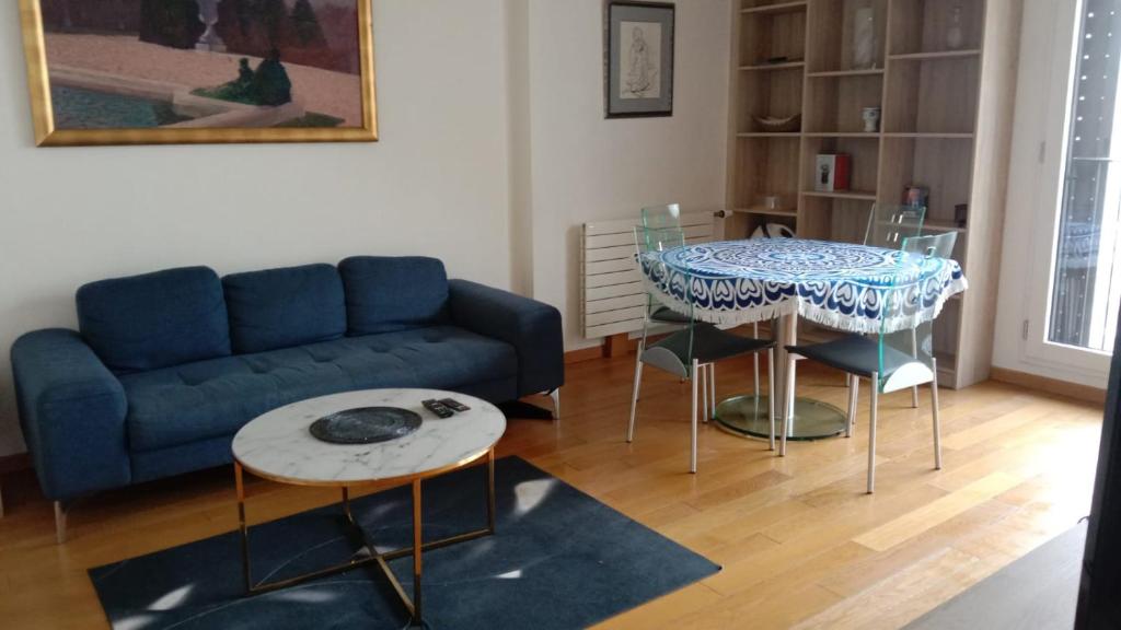 uma sala de estar com um sofá, uma mesa e cadeiras em Au pied de la Tour Eiffel résidence familiale 2bdr em Paris