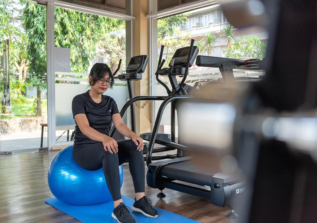 a woman sitting on an exercise ball in a gym at Oakwood Hotel & Apartments Taman Mini Jakarta in Jakarta