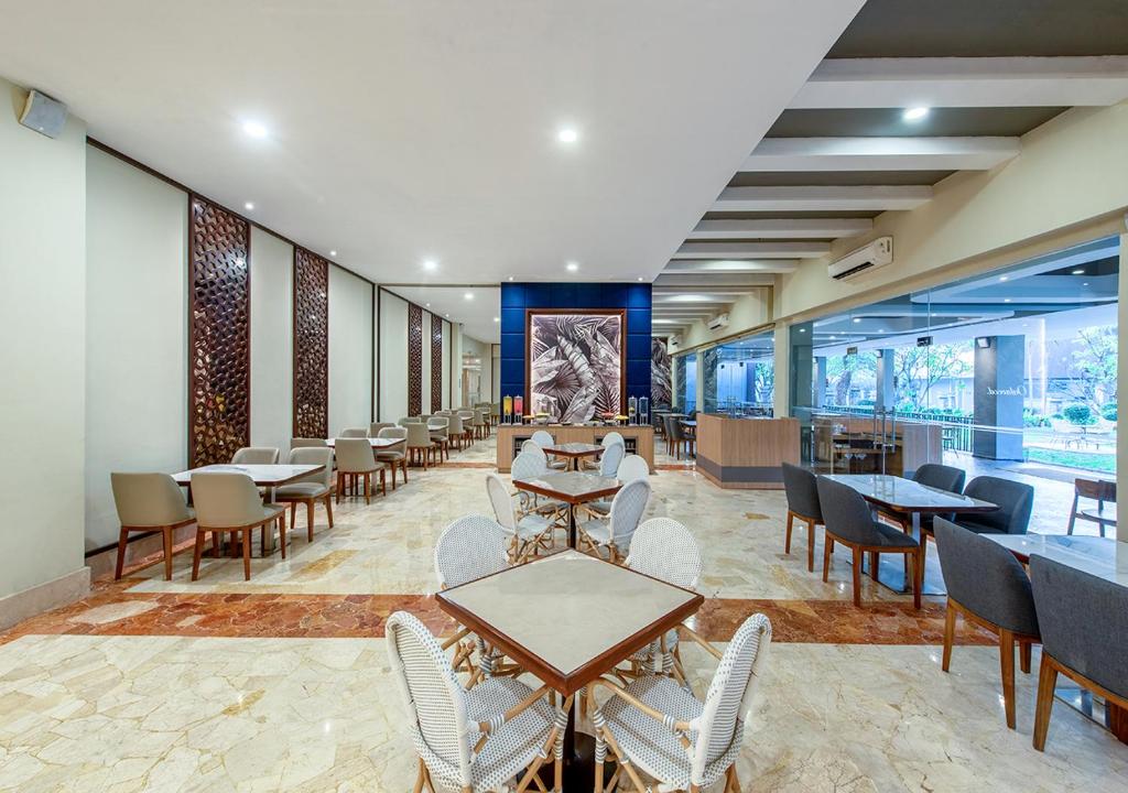 a dining room with tables and chairs and windows at Oakwood Hotel & Apartments Taman Mini Jakarta in Jakarta