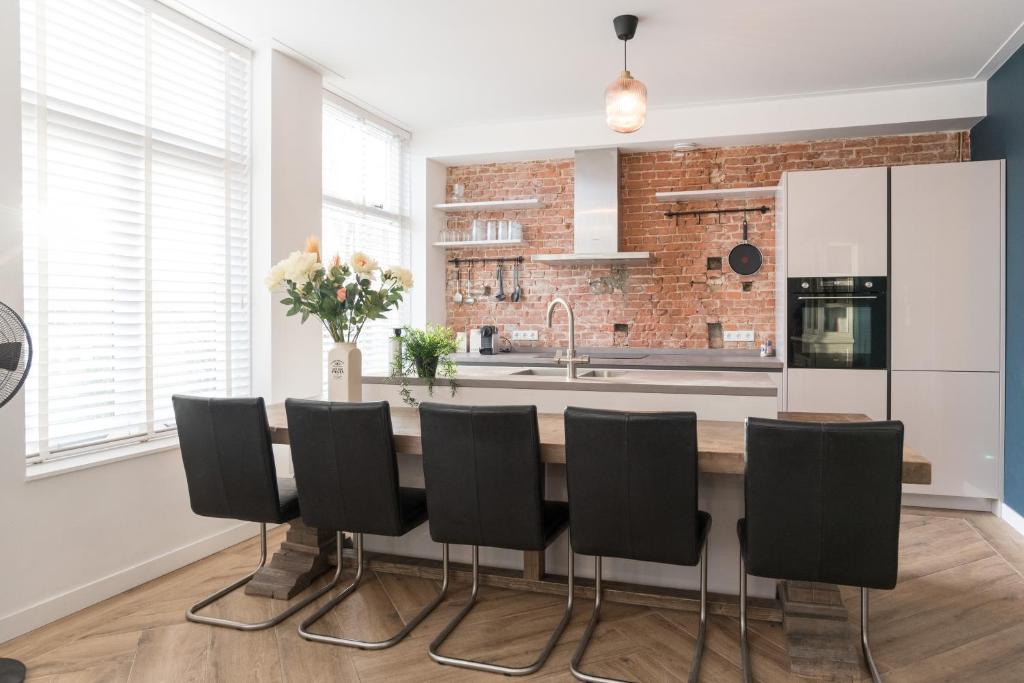 a kitchen with a table and black chairs at Kampervest Apartment Haarlem in Haarlem