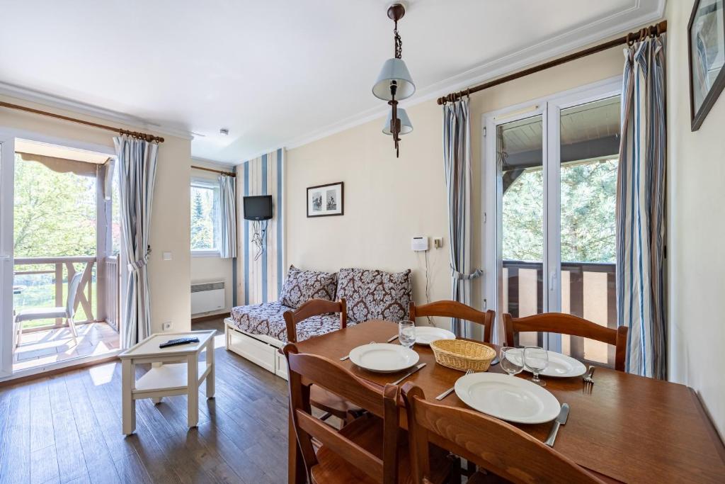 ein Wohnzimmer mit einem Tisch, Stühlen und einem Sofa in der Unterkunft Le Swing - Résidence avec piscine chauffée in Deauville