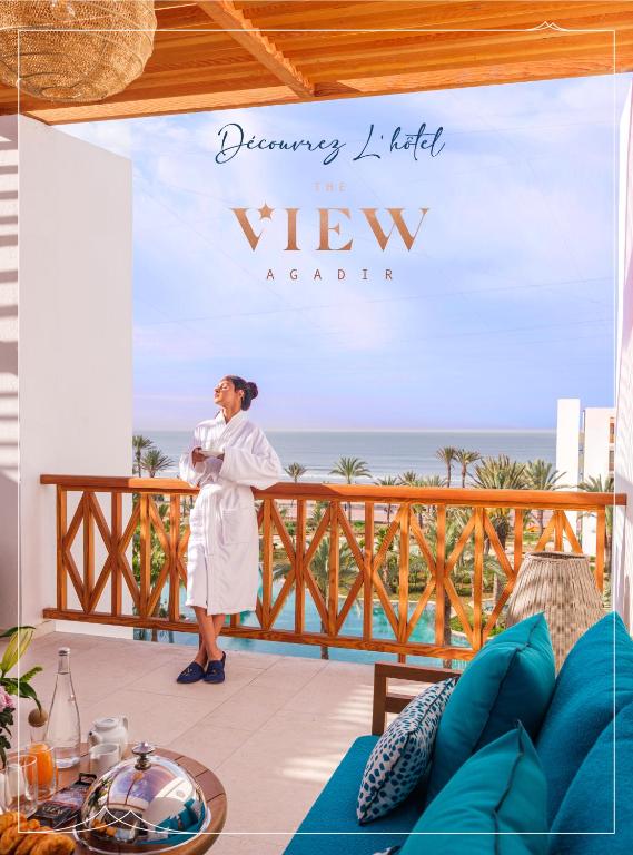 a man standing on a balcony with the ocean in the background at The View Agadir in Agadir