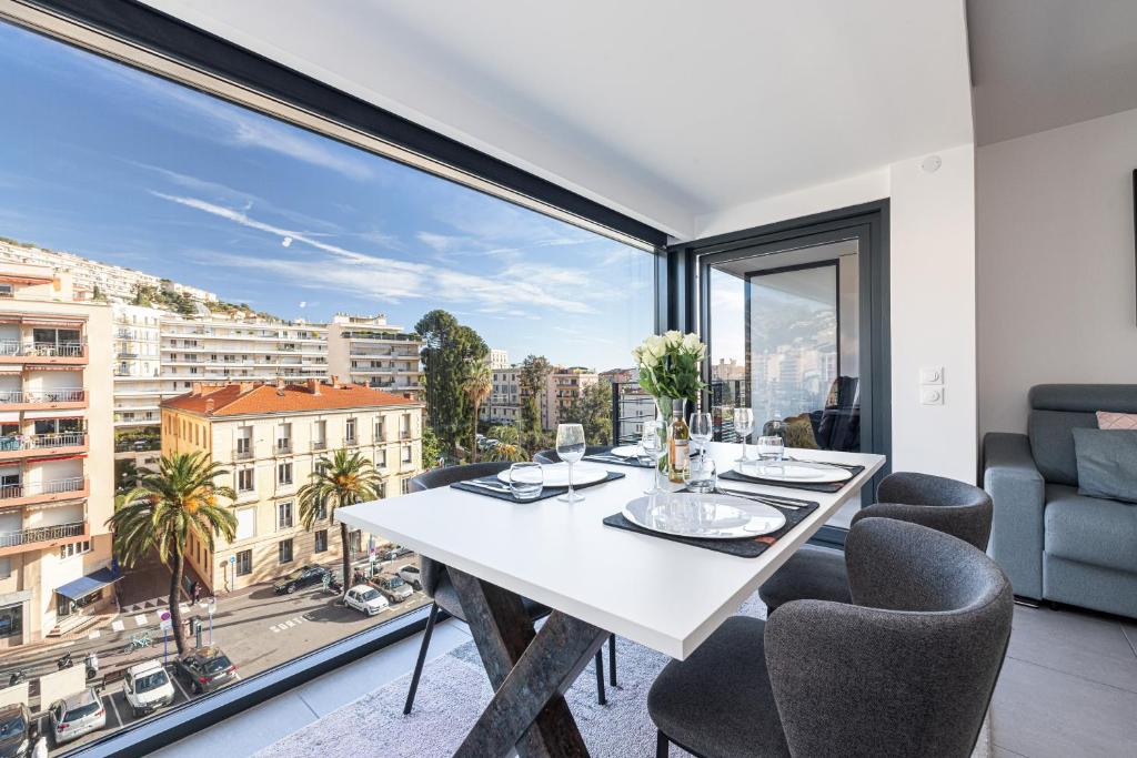 a dining room with a white table and chairs and a large window at Beautiful New Apartment in Menton