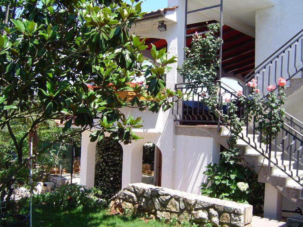 uma casa branca com uma escada e flores em Apartmani Rozi em Umag