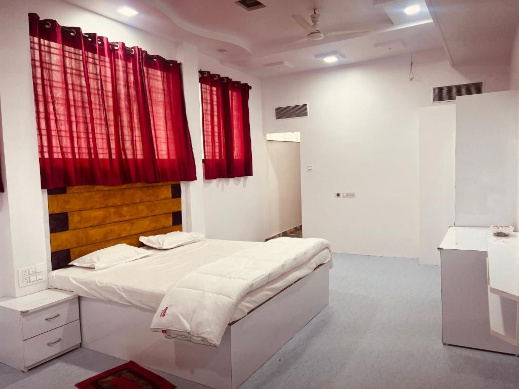a white bedroom with red curtains and a bed at Lotus in Nagpur