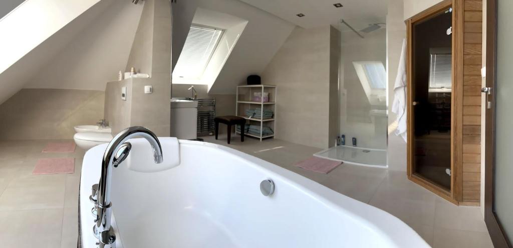 a white bathroom with a tub and a toilet at Lux Apartmán Centrum in Topoľčany