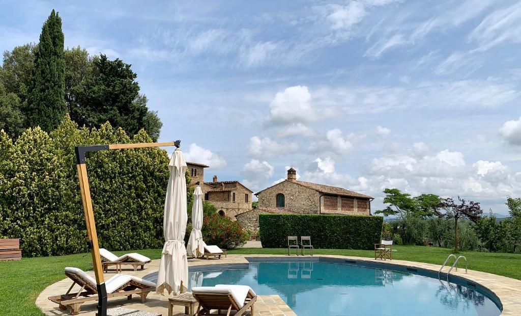 a swimming pool with chairs and a house at Poggiosole in Tavarnelle in Val di Pesa