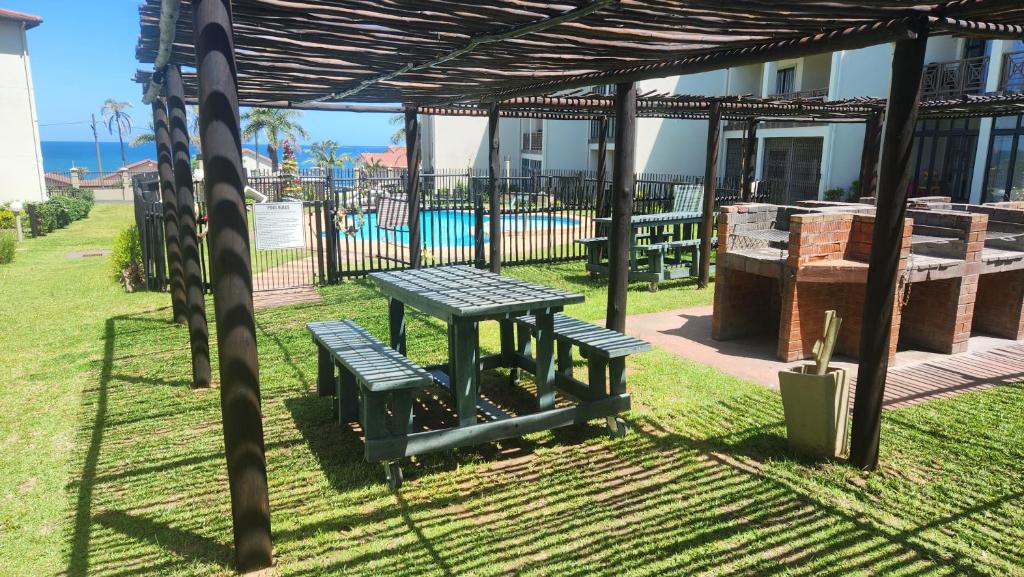 a picnic table and two benches under a pergola at Topanga 17 in Uvongo Beach