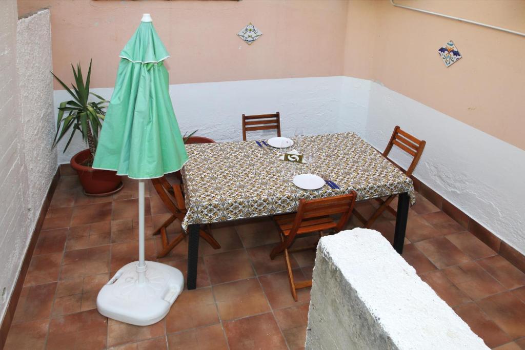 una mesa con sillas y una sombrilla en el balcón en Appartamento con Cortile Privato, en Santo Stefano di Camastra