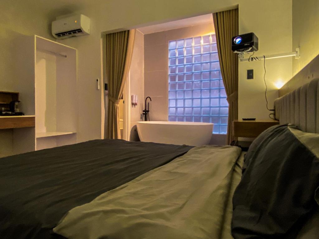 - une chambre avec un lit, une baignoire et une fenêtre dans l'établissement Zeus Living - City Central, à Hô-Chi-Minh-Ville