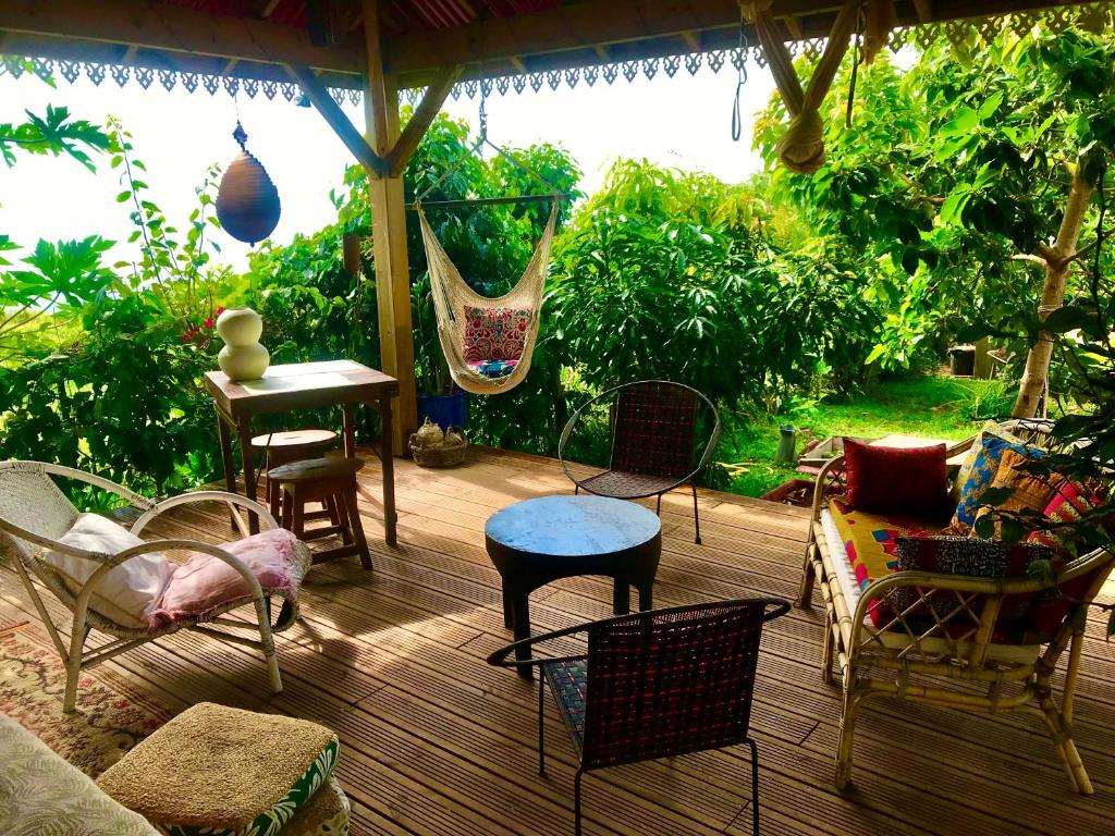 un patio avec des chaises, une table et une balançoire dans l'établissement Canne Mapou, l'Escale Nature, à Trois Bassins