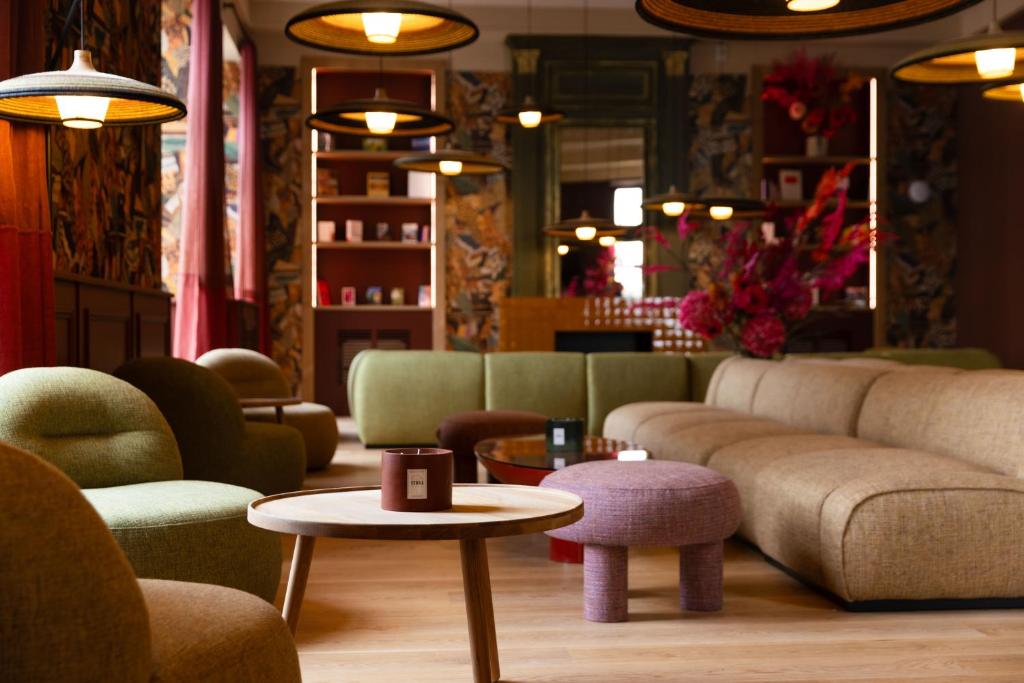 uma sala de estar com um sofá, mesas e cadeiras em Serra Boutique Hôtel em Agen