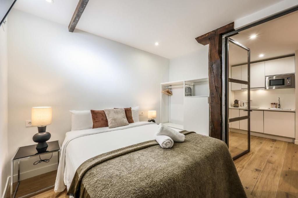 ein Schlafzimmer mit einem großen weißen Bett und einem Spiegel in der Unterkunft Encantador apartamento Plaza del Callao in Madrid