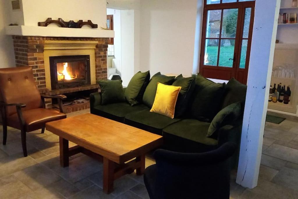 sala de estar con sofá verde y chimenea en Escapade Rurale: Maison 10 pers, jardin, feu cheminée, en Coulonges