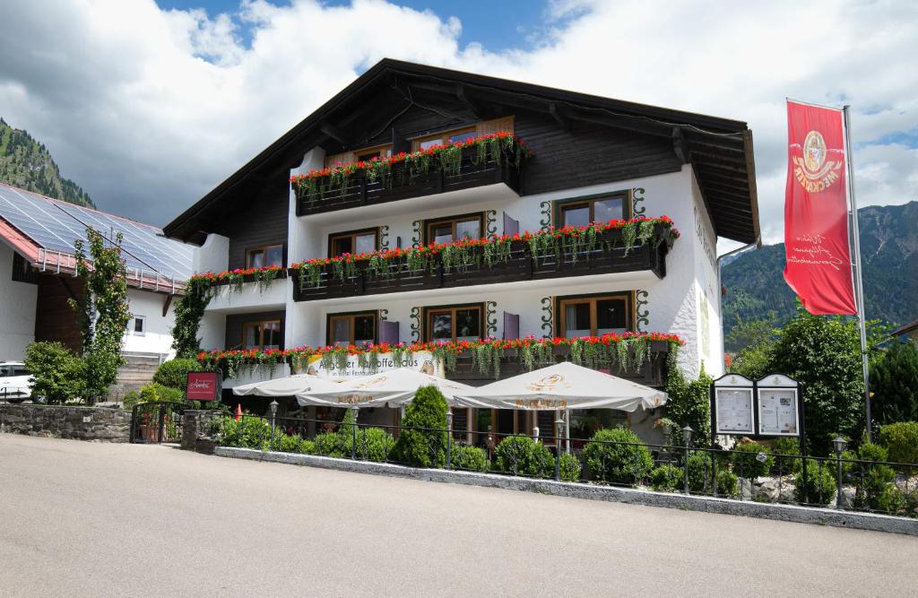 un edificio con flores y sombrillas delante de él en Hotel Restaurant Amadeus, en Bad Hindelang