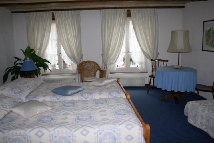 a bedroom with a bed and a table and windows at Hotel zum alten Schweizer in Twann