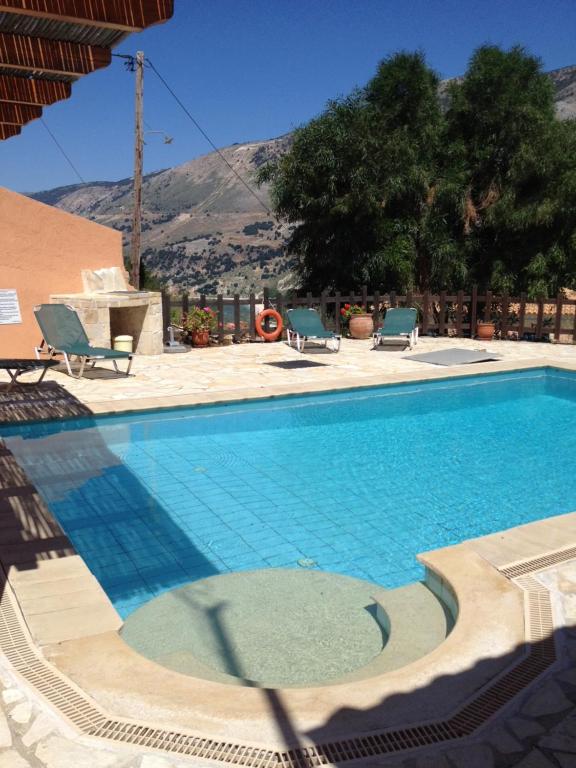 Ein Swimmingpool mit Liegestühlen und einem Berg im Hintergrund in der Unterkunft Villa Midas in Zóla