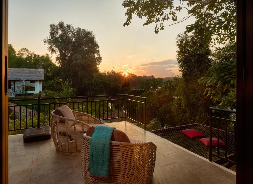 a balcony with wicker chairs and the sunset in the background at The Namkhan in Luang Prabang