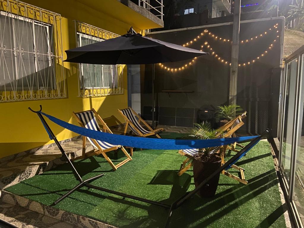 a hammock and chairs with an umbrella on a patio at República Descolada! Ótima localização! Quarto p/ casal! in Florianópolis