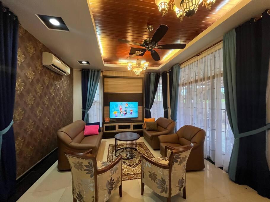- un salon avec une table, des chaises et une télévision dans l'établissement Tokwan Homestay 2 - Homestay with private kid's pool, à Kuala Kedah
