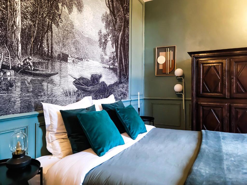 een slaapkamer met een bed met een schilderij aan de muur bij Domaine Le Clos de la Source - Petit déjeuner buffet in Montrichard