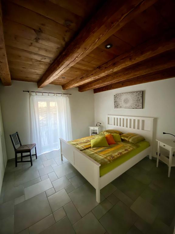 a bedroom with a bed and a chair and a window at Cà dal Gascia in Intragna