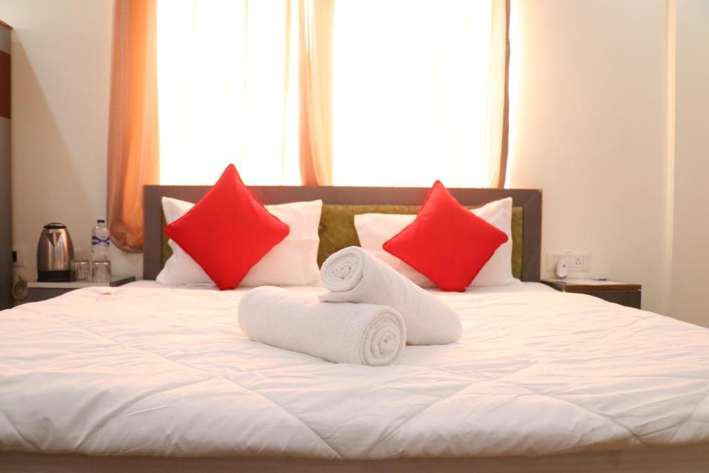a bed with red and white pillows and towels at Yoga Vairagyam Tapovan in Rishīkesh