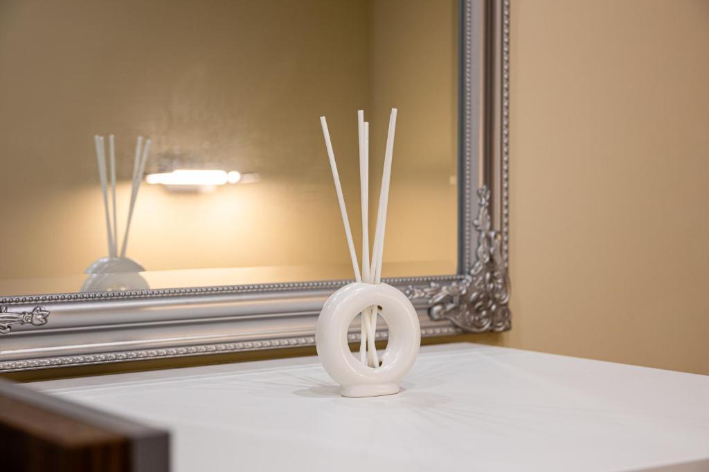a white vase on a table in front of a mirror at GrigorasNCo Studio Apartments in Budapest
