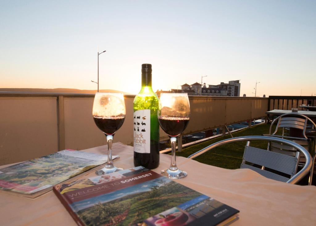 Monaco Hotel في ويستون سوبر مير: طاولة مع كأسين من النبيذ وكتاب