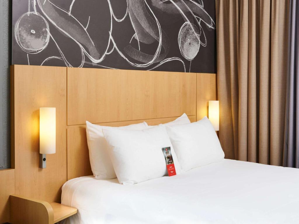 Habitación de hotel con cama con almohadas blancas en ibis Annecy Centre Vieille Ville, en Annecy