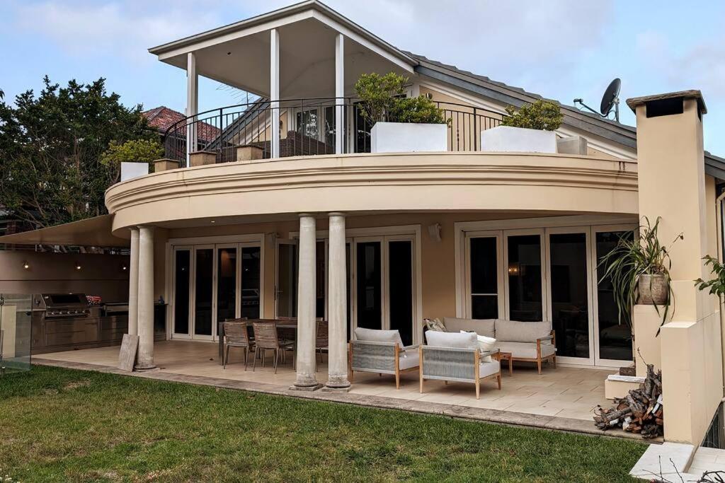 een huis met een balkon met een tafel en stoelen bij Tranquil Escape at Balmoral Beach in Sydney