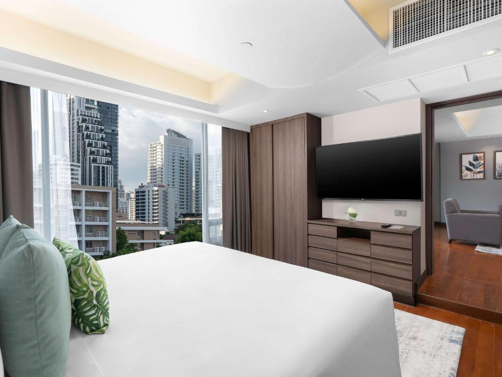 a bedroom with a large white bed and a large window at Novotel Living Bangkok Sukhumvit Legacy in Bangkok