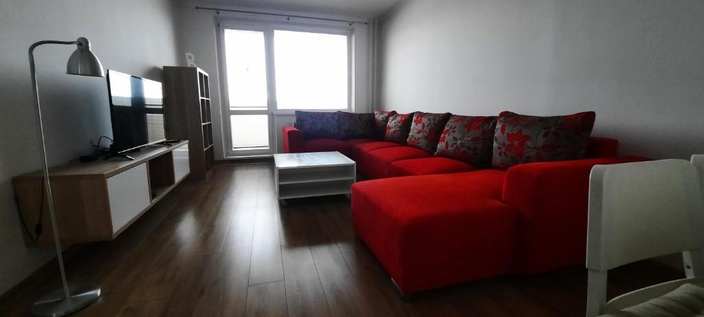 Stropkovにあるplne vybavený 3 izbový apartmánのリビングルーム(赤いソファ、テレビ付)