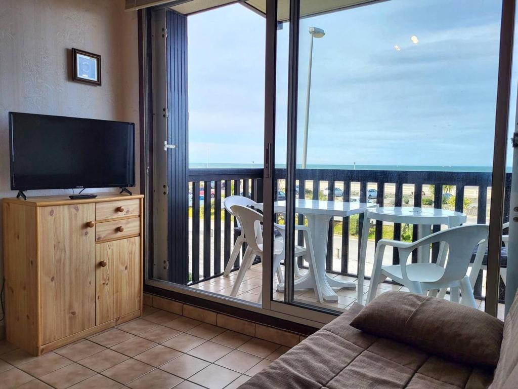 un salon avec une télévision et un balcon avec une table dans l'établissement Appartement familial centre ville avec parking et animaux permis - FR-1-465-90, à Merville-Franceville-Plage