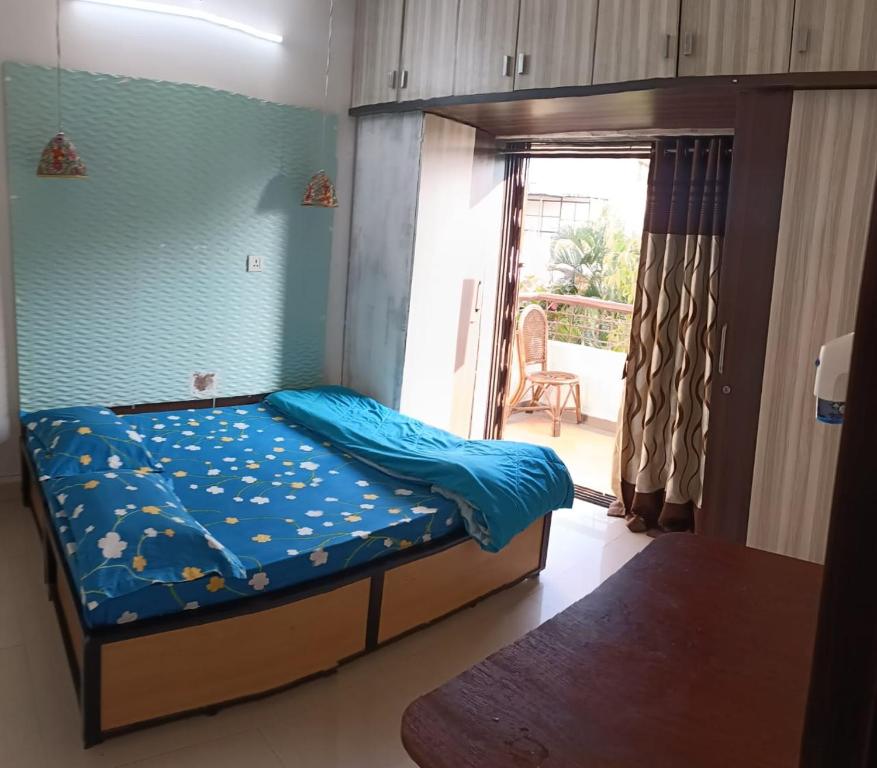 a bedroom with a bed with blue sheets and a balcony at Birds Nest in Pune