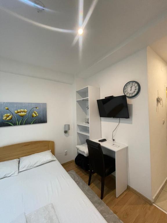 a bedroom with a bed and a desk and a clock at Apartments & Rooms L E F T RIVER Belgrade in Belgrade