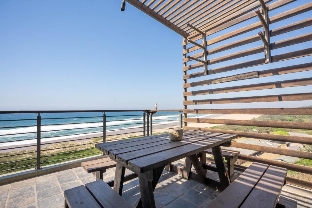 einen Picknicktisch aus Holz auf einem Balkon mit Blick auf den Strand in der Unterkunft The Spot on the Beach in Kingsborough